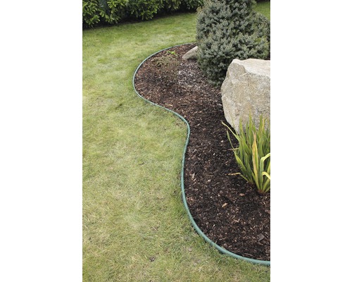 Zahradní scéna s trávníkem, záhon s mulčovací kůrou, kameny, rostlinami a obrubníkem trávníku