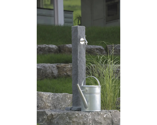Zahradní scéna s kamenným odběrným místem vody a konví