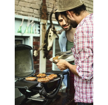 Dva muži grilují plněné žampiony na kulatém grilu venku.