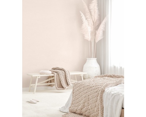 Světlá ložnice s postelí, lavicí, přikrývkami, polštáři a pampovou trávou ve váze