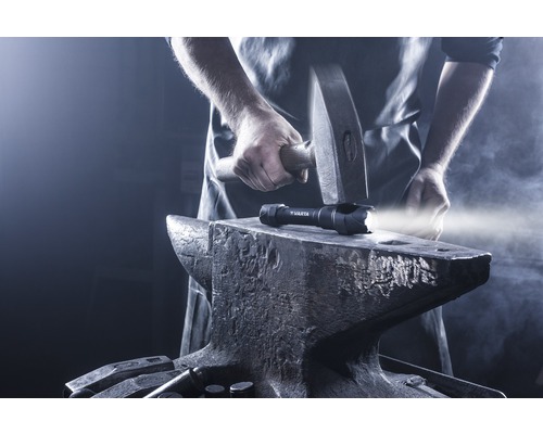 Svítilna Varta na kovadlině, s kladivem nad ní