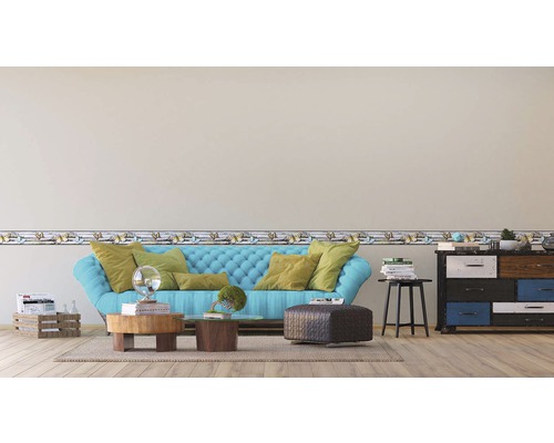 Obývací pokoj s modrou pohovkou, konferenčním stolkem, komodou a bordurou s motýlím vzorem