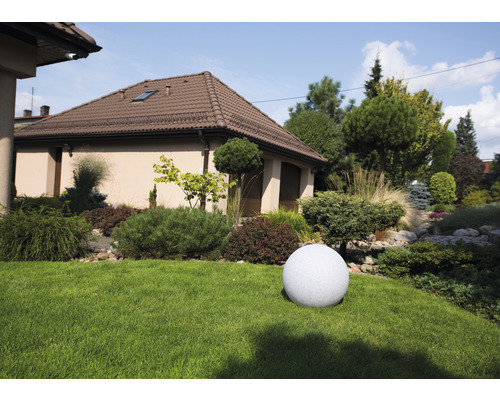 Kulaté zahradní svítidlo v předzahrádce s domem v pozadí