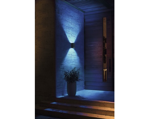 Osvětlený vstupní prostor s venkovní nástěnnou lampou, vchodovými dveřmi a schody