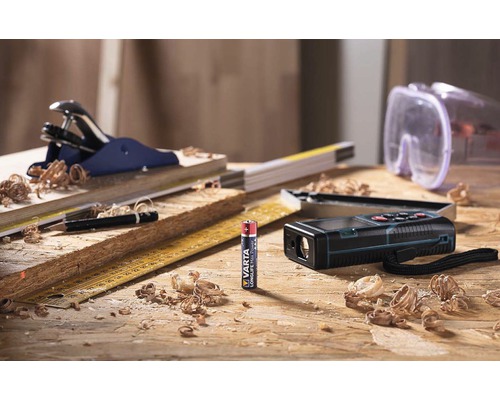 Pracovní stůl s hoblíkem, tužkou, skládacím metrem, laserovým dálkoměrem, ochrannými brýlemi a baterií Varta