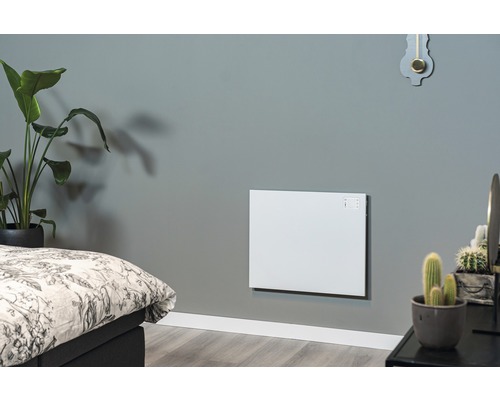 Obývací pokoj s namontovaným bílým nástěnným topením vedle postele a rostlin