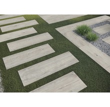 Zahradní chodník s obdélníkovými dlaždicemi s vzhledem dřeva na trávníku