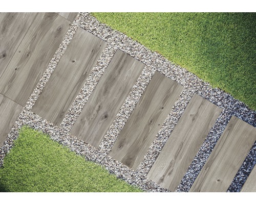 Zahradní scéna s chodníkovými dlaždicemi se vzhledem dřeva, lemovaná štěrkem a trávníkem