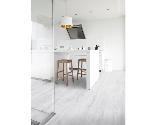 Světlá kuchyně s kuchyňským ostrovem, barovými stoličkami a laminátovou podlahou s dřevěným vzhledem.