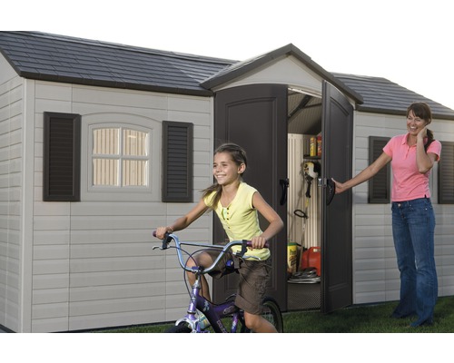 Zahradní bouda s otevřenými dveřmi, hrající si dítě na kole a žena