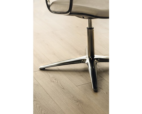 Detail kancelářské židle s chromovanou nohou na dřevěné podlaze