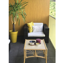 Balkon s ratanovým křeslem, stolem, polštáři a jukou v květináči