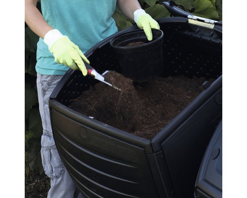 Osoba plní kompostér zeminou.