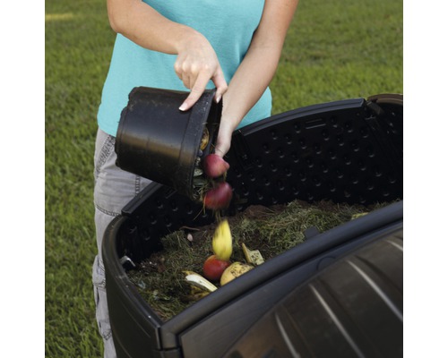 Osoba vysypává bioodpad do kompostéru na zahradě.