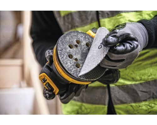 Muž mění brusný papír na excentrické brusce.