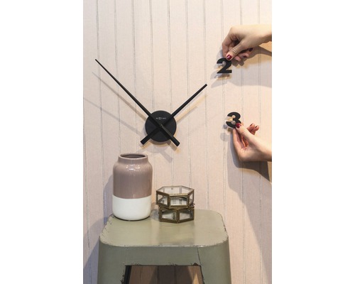 Nástěnné hodiny s ručičkami a číslicemi k nalepení, váza a dekorativní skleněné nádoby na stoličce.