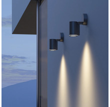 Dvě válcové nástěnné lampy osvětlují stěnu domu