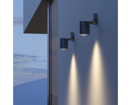 Dvě válcové nástěnné lampy osvětlují stěnu domu