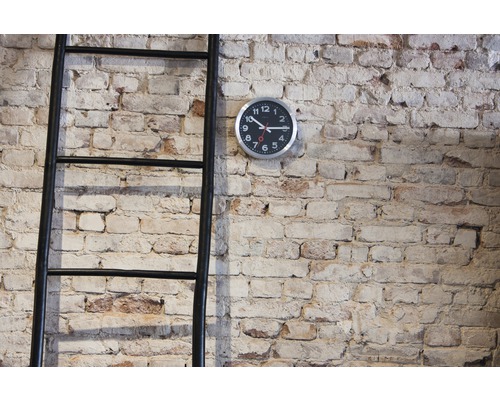 Dekorativní žebřík a nástěnné hodiny před cihlovou zdí