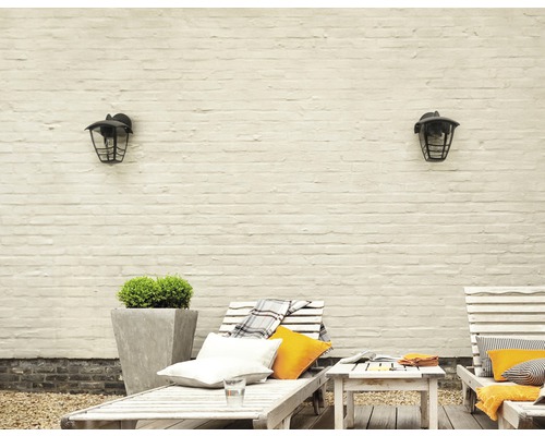 Venkovní prostor se zahradními lehátky, odkládacím stolkem, květináčem a dvěma venkovními světly na cihlové zdi