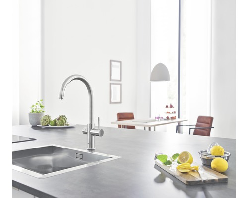 Kuchyňský dřez s baterií na pracovní desce s citrony a bylinkami.