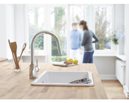 Kuchyňský dřez s kohoutkem na pracovní desce ve světlé kuchyni