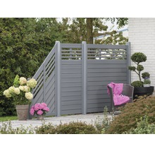 Zahradní scéna s šedým soukromým plotem, rostlinami a posezením