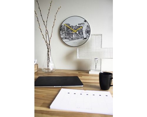 Dekorativní psací stůl s nástěnnými hodinami, notebookem, šálkem a kalendářem.