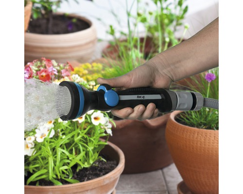 Ruka drží zahradní stříkací pistoli for.q a zalévá rostliny.