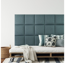 Nástěnné panely jako čelo postele nad matrací na dřevěné paletě s polštáři a dekou