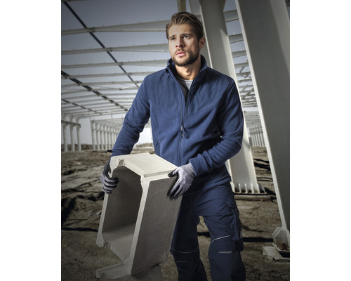 Muž v pracovním oděvu nese betonovou formu