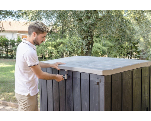 Muž otevírá zahradní truhlu s víkem venku