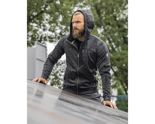 Muž s vousy nosí mikinu s kapucí.