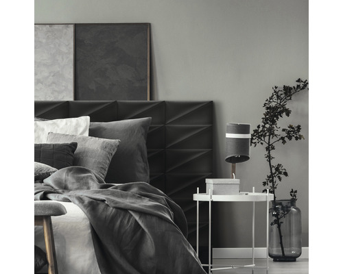 Ložnice s postelí, nočním stolkem a dekorací v šedých tónech.