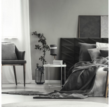 Ložnice s postelí, nočním stolkem, lampou a židlí.