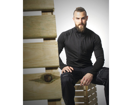 Muž v pracovním oděvu sedí na dřevěné paletě