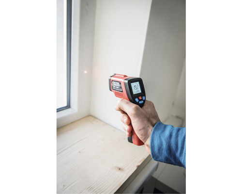 Ruka s infračerveným teploměrem pro měření teploty u okna