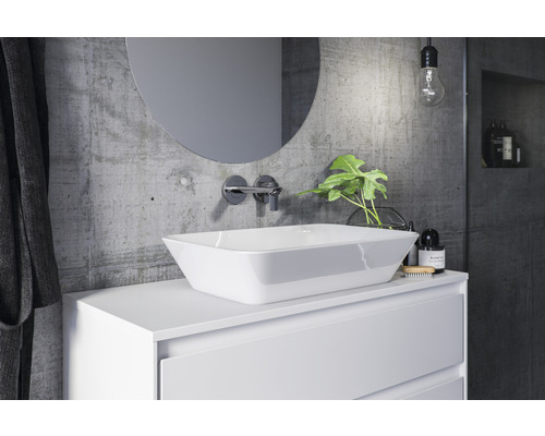 Moderní koupelna s umyvadlem na desku, kulatým zrcadlem a betonovou stěnou