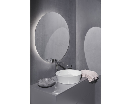 Koupelna s kulatým zrcadlem, umyvadlem na desku, baterií a umyvadlovou skříňkou