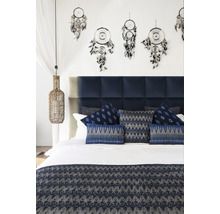 Ložnice s modrým čelem postele, ozdobnými polštáři, přehozem a lapači snů