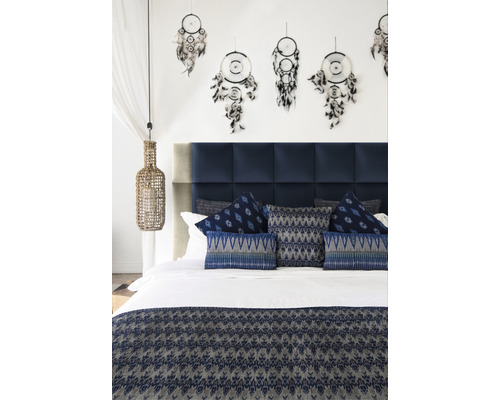 Ložnice s modrým čelem postele, ozdobnými polštáři, přehozem a lapači snů