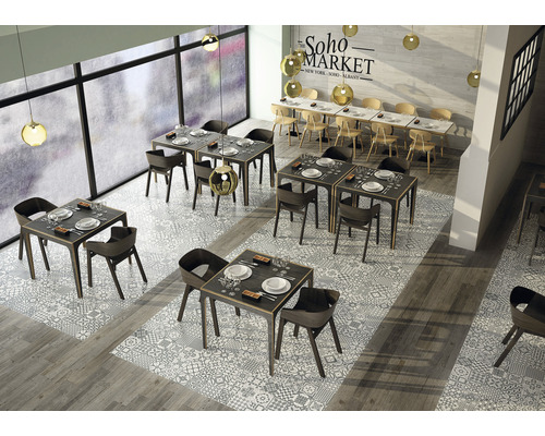 Interiér restaurace se stoly a židlemi na vzorované dlažbě.