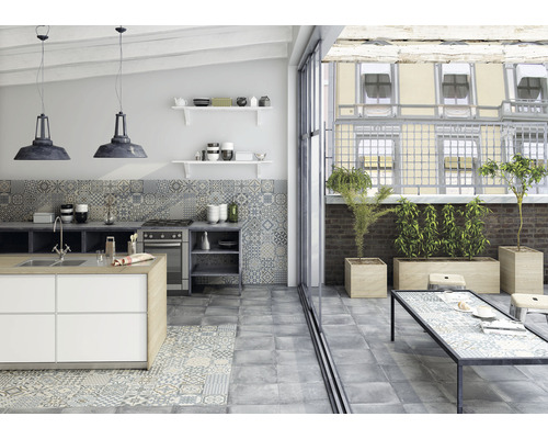 Světlá kuchyně s dlažbou a obkladem ve vintage stylu, kuchyňský ostrůvek a vstup na balkon se stolem a osázením