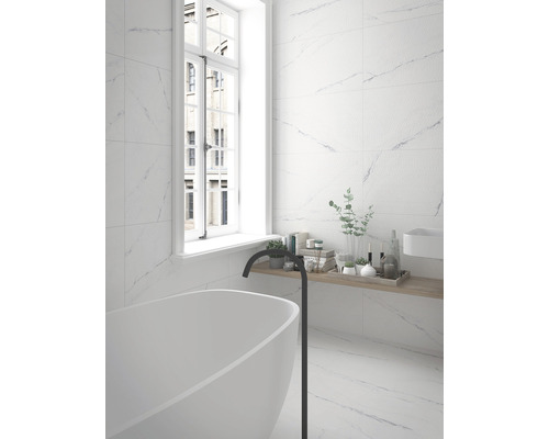 Světlá koupelna s volně stojící vanou, baterií a obkladem stěn s mramorovým vzhledem