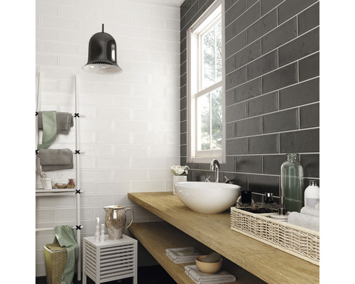 Koupelna s bílými a černými obkladačkami, umyvadlová skříňka s dřevěnou deskou a bílým umyvadlem na desku