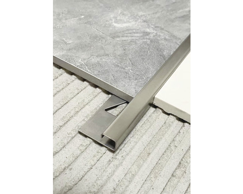 Kovová dlažební lišta mezi dvěma dlaždicemi