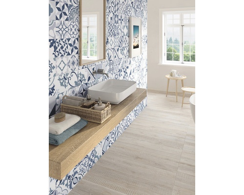 Světlá koupelna s modrými vzorovanými obklady, umyvadlem a dřevěnou podlahou