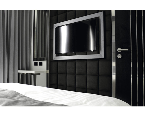 Ložnice s čalouněnou stěnou, televizí a nočním stolkem