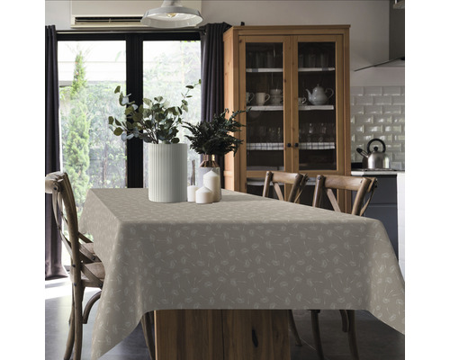 Jídelní stůl se vzorovaným ubrusem, květinové vázy a židle ve světlé místnosti.