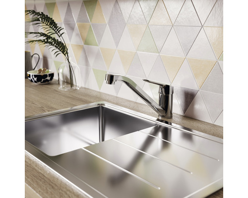 Nerezový dřez s odkapávací plochou a baterií před trojúhelníkovými obkladačkami